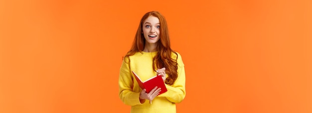 Free photo inspired and upbeat dreamy fascinated redhead girl writing down interesting lecture smiling and gazi