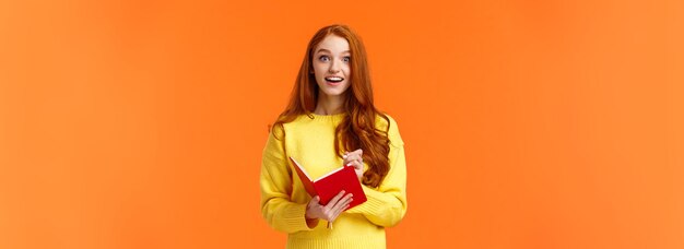 Inspired and upbeat dreamy fascinated redhead girl writing down interesting lecture smiling and gazi