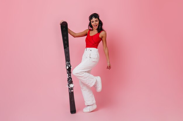 Inspired woman in white pants holding skis