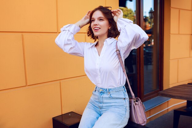 Donna ispirata con i peli della camicia godendo i fine settimana in soleggiata città europea. indossa una camicia casual.