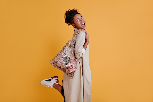 Inspired woman with string bag standing on one leg