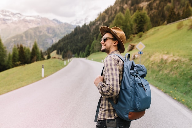 Inspired young man with sincere smile looking around enjoying amazing italian nature and forest landscape