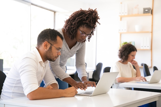 Instructor helping intern to start working laptop