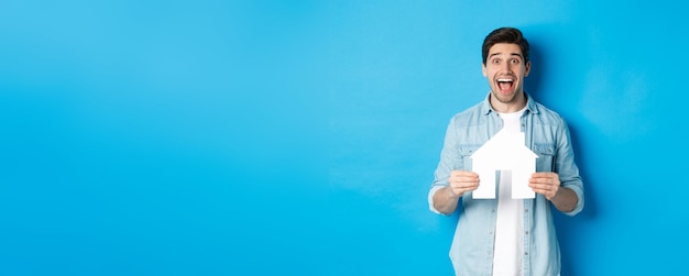 Insurance mortgage and real estate concept happy man holding house model and smiling excited buying