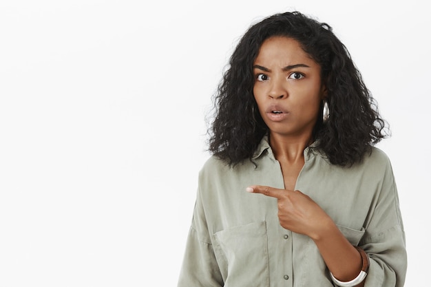 Intense unsure and confused African American female left pointing