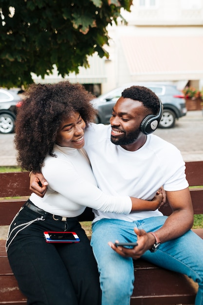 Free photo intercultural friends sitting on bench while hugging