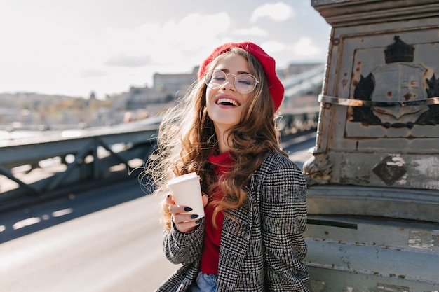 Interested caucasian girl in vintage outfit drinking coffee during trip around europe