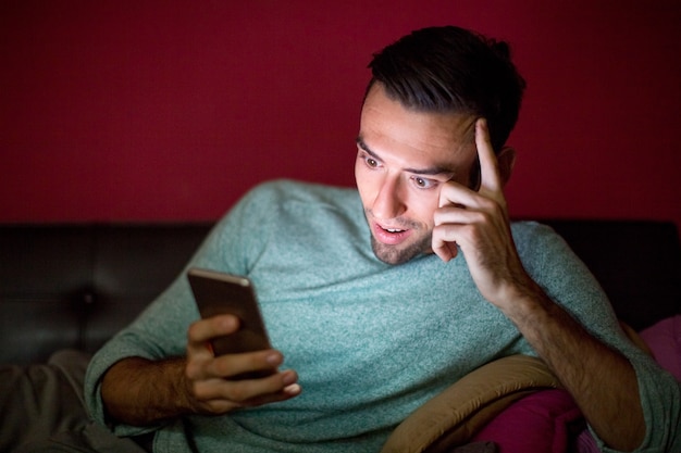 Interested Man Using Smartphone on Sofa at Night