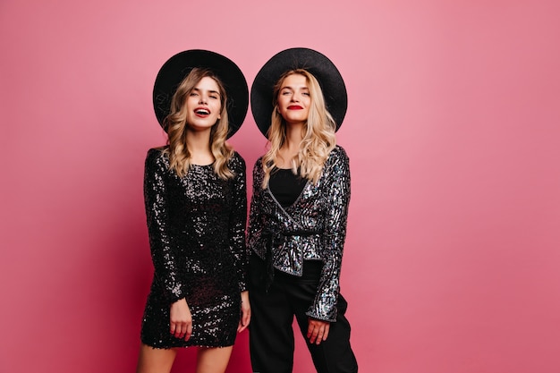 Interested woman in shiny clothes waiting for party. elegant young ladies in hats.