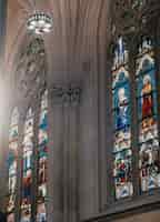 Foto gratuita l'interno di una chiesa con pareti grigie e dipinti a mosaico di santi religiosi su finestre