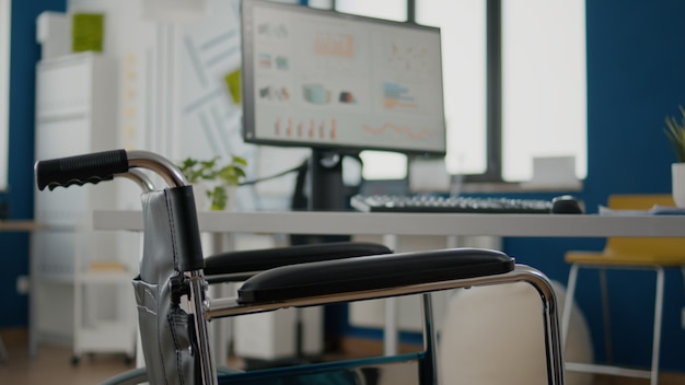 Interior of cozy light company room with wheelchair parked near desk