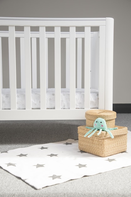 Free photo interior of light baby room with a modern cozy crib and woven wicker boxes on a soft starry carpet