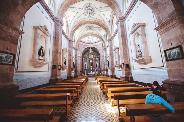 Interior shot of a church with people sitting on the wooden benches