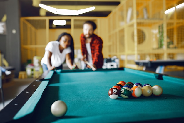 International couple playing a billiard in a club