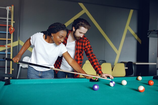 International couple playing a billiard in a club