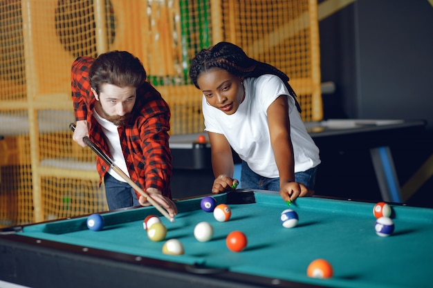 Free photo international couple playing a billiard in a club