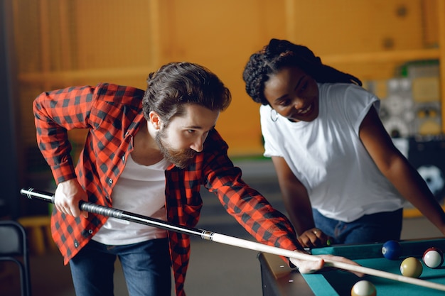 Free photo international couple playing a billiard in a club