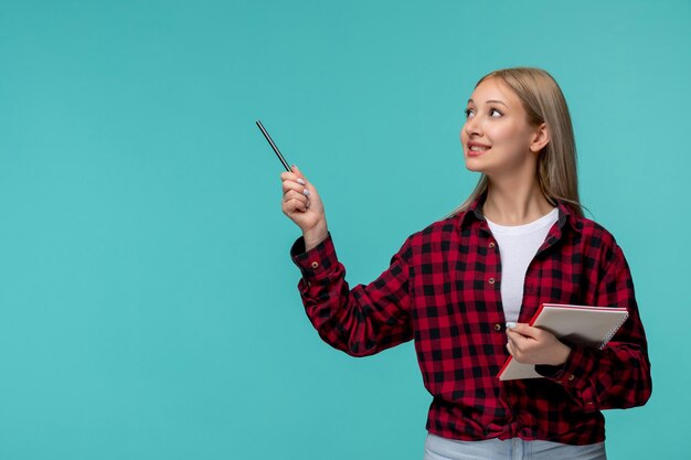 International students day cute blonde girl in red checked shirt happy holding a notebook and pen