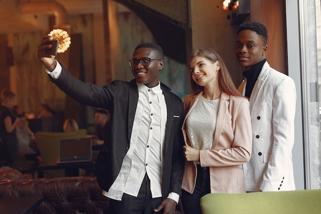 Free photo internationals people standing in a cafe with mobile phone