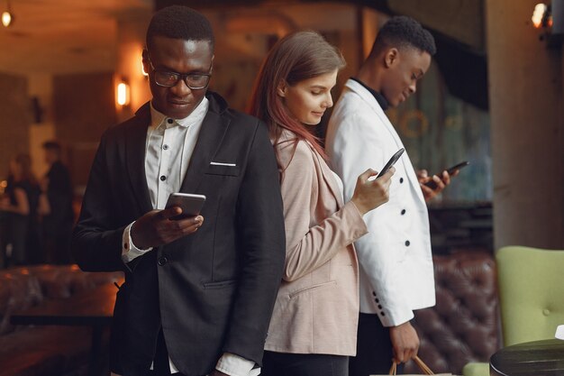 Internationals people standing in a cafe with mobile phone