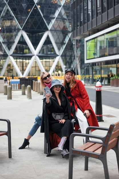 Free photo internet celebrity taking a selfie with friends while sitting on a bench