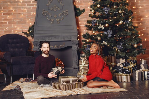 Internetional people at home. Couple in a Christmas decorations. African woman and caucasian man.