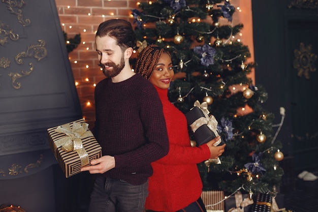 Internetional people at home. Couple in a Christmas decorations. African woman and caucasian man.