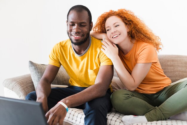 Interracial couple smiling at a laptop