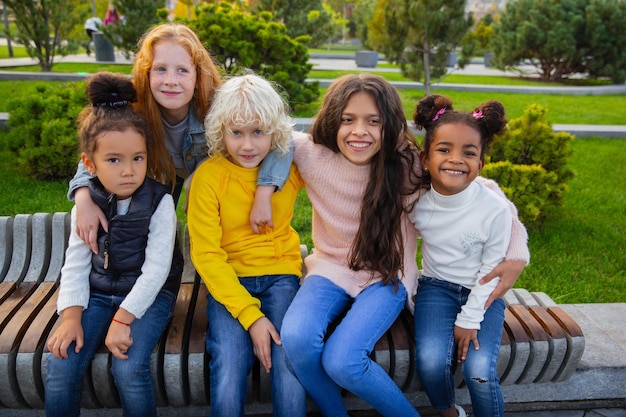 Gruppo interrazziale di bambini, ragazze e ragazzi che giocano insieme al parco in una giornata estiva