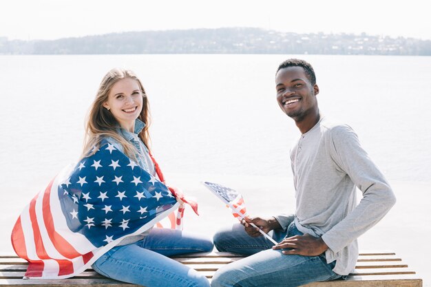 Interracial patriotic couple sitting on bench