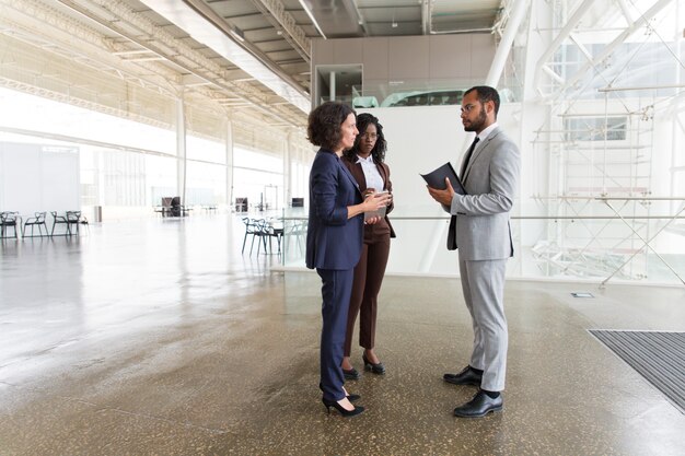 Interracial team discussing project in office hallway