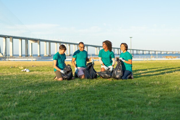 Interracial volunteer team picking up rubbish from lawn