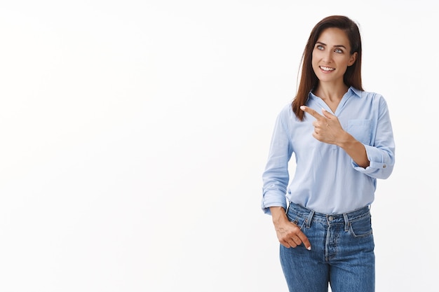 Intrigued professional confident female empowered entrepreneur, look sideways, pointing gaze left curious, like good product, interesting project concept, stand white wall pleased