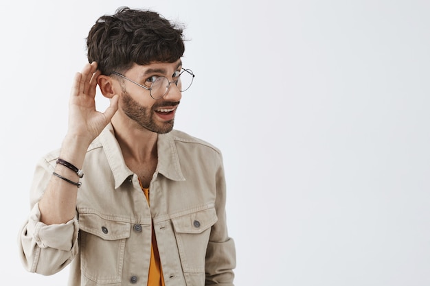 Intrigued stylish bearded guy posing against the white wall