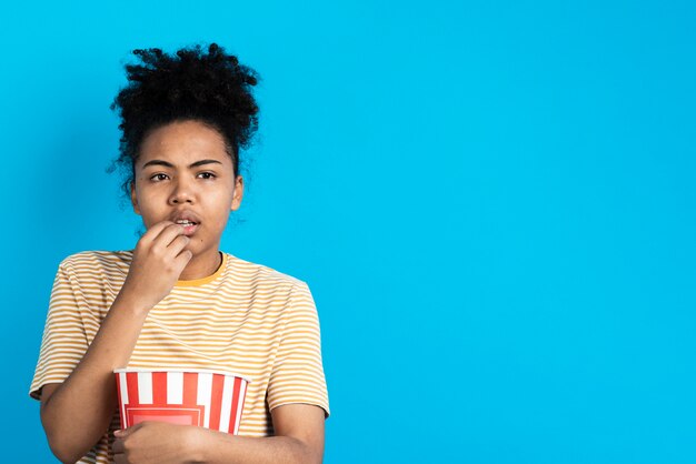 Intrigued woman posing while eating popcorn