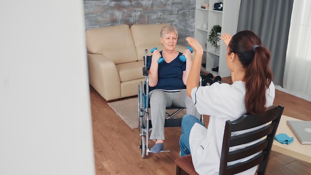 Invalid old woman in wheelchair doing rehab training with support from doctor. Disabled handicapped old person recovering professional help nurse, nursing retirement home treatment and rehabilitation