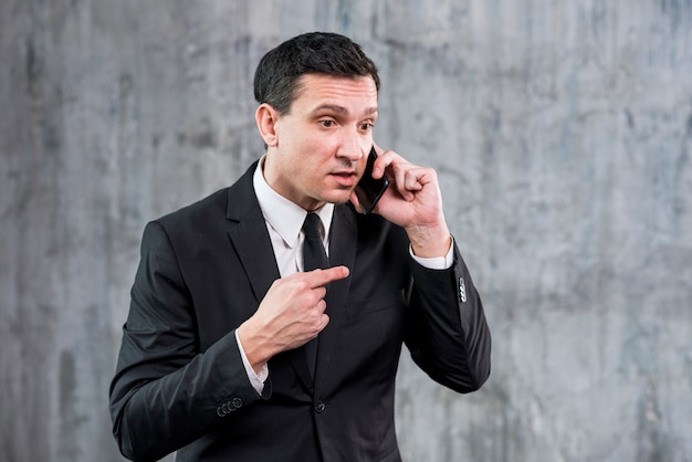 Irritated adult businessman speaking on phone