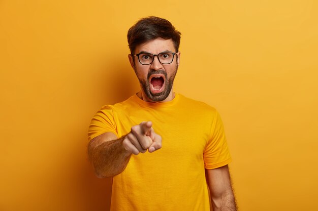 Irritated bearded young man shouts angrily, accuses someone