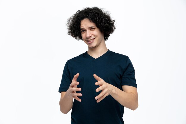 Irritated young handsome man keeping hands in air looking at camera isolated on white background