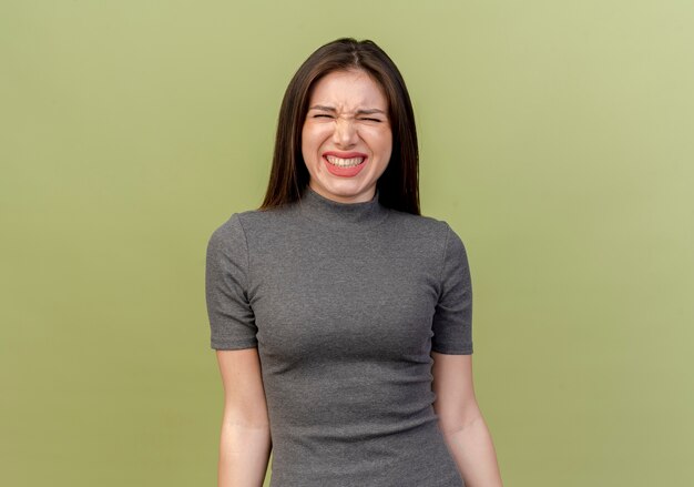 Irritated young pretty woman looking at camera isolated on olive green background with copy space