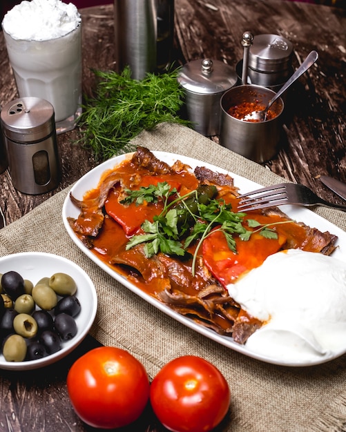 Free photo iskender kebab garnished with tomato and parsley served with yogurt