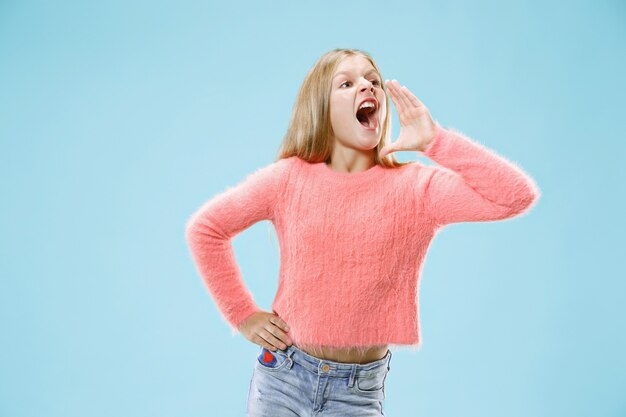 Isolated on blue young casual girl shouting