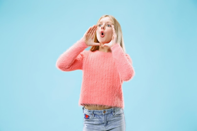 Foto gratuita isolato su blu giovane ragazza adolescente casual gridando in studio