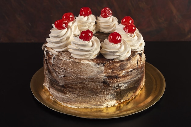 Изолированный коричневый торт с бело-красной начинкой на черном столе