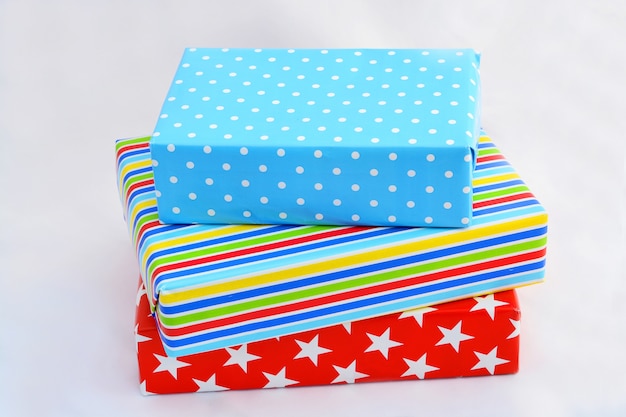 Isolated closeup shot of gift boxes in colorful wrapping stacked on top of  each on white background