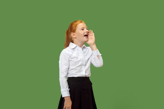 Isolated on green young casual teen girl shouting at studio