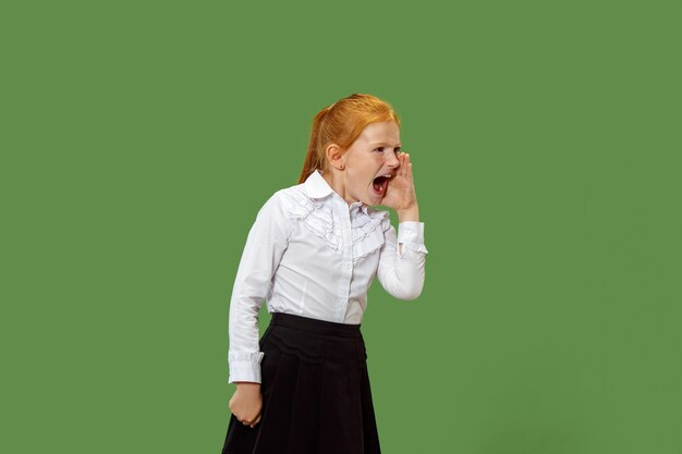 Isolated on green young casual teen girl shouting at studio