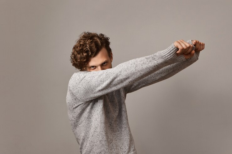 Free Photo isolated image of mysterious handsome guy with trendy voluminous curly hairstyle dancing keeping face close to shoulder and outstretching arms,