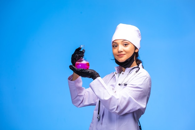 Изолированная медсестра в руке и маске держит химическую фляжку и демонстрирует это.