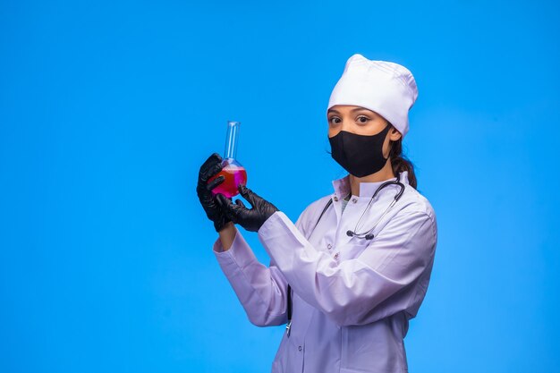 Isolated nurse in hand and face mask makes test and shows the flask. 